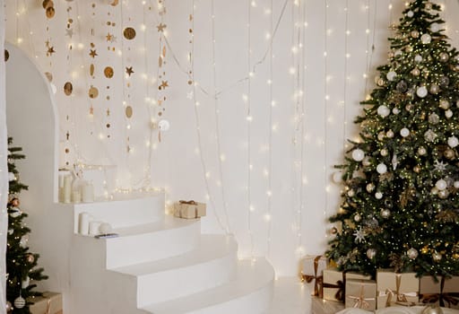 A large Christmas tree in the living room, decorated with garlands and light balloons. Bright Christmas interior with a white staircase