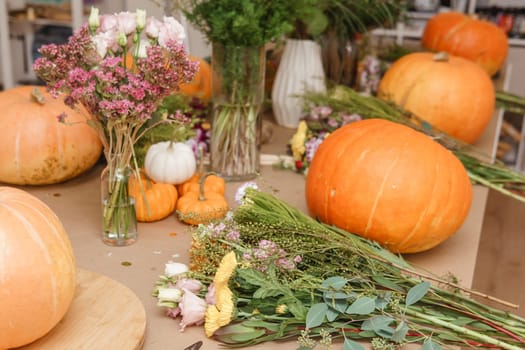 Flower arrangement in a pumpkin, autumn interior decor. Creating handmade autumn decor