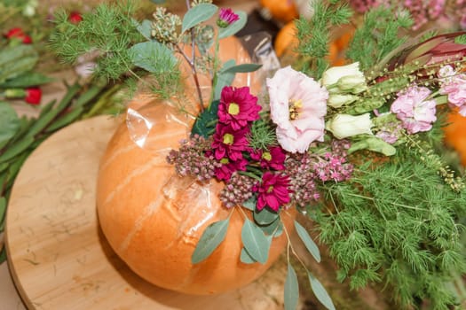 Flower arrangement in a pumpkin, autumn interior decor. Creating handmade autumn decor