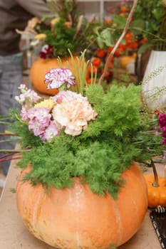 Flower arrangement in a pumpkin, autumn interior decor. Creating handmade autumn decor