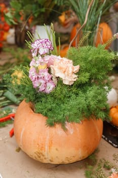 Flower arrangement in a pumpkin, autumn interior decor. Creating handmade autumn decor