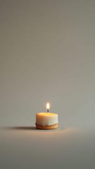 A small birthday cake with a single candle on minimalist background.