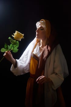 The girl in vibrant traditional clothing gazes at a yellow rose, capturing a moment of beauty and contemplation, reminiscent of biblical times.