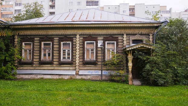 A vintage house with weathered faade, juxtaposed against modern buildings and greenery