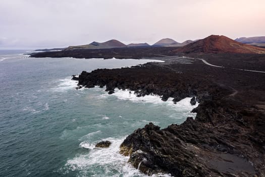 drone view of foamy sea breaking over the volcanic coast of Los Hervideros in Yaiza, Lanzarote at Canary Islands, Spain, concept of wild nature