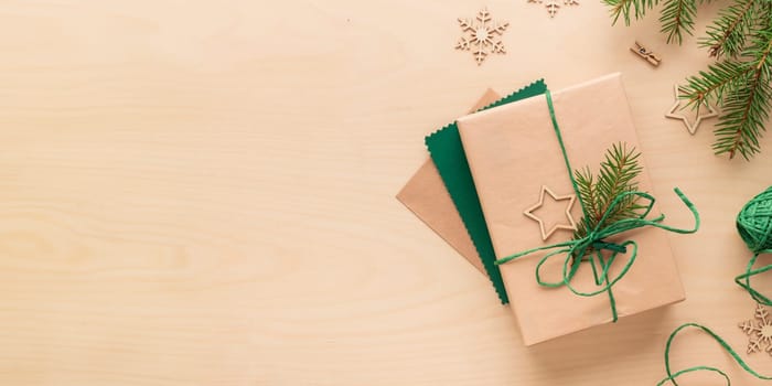 Christmas and zero waste, eco-friendly natural packaging gift in craft paper and a greeting card on a wooden table, eco Christmas holiday concept, eco decor banner with copy space