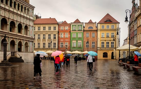 Tourists Under Umbrellas At Market Square In Poznan, Poland, Create A Vibrant Scene