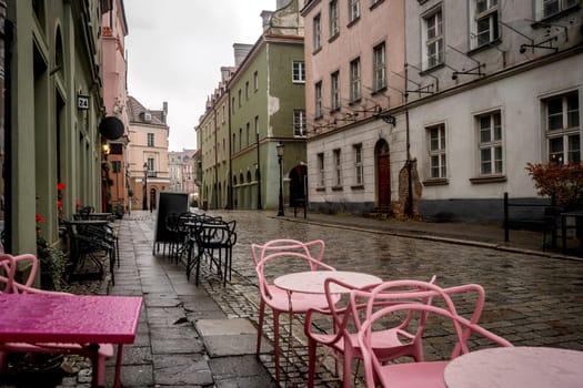 Pink Tables Of A Cafe Brighten Up A Rainy Alley In An Old Polish Town