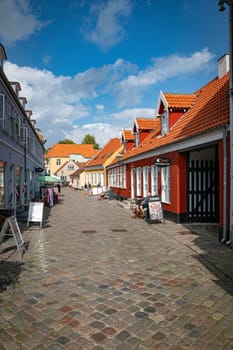 ebeltoft,denmark,30-08-2024:Quaint European street featuring vibrant buildings and cobblestone path under a blue sky. A serene atmosphere, perfect for exploringebeltoft