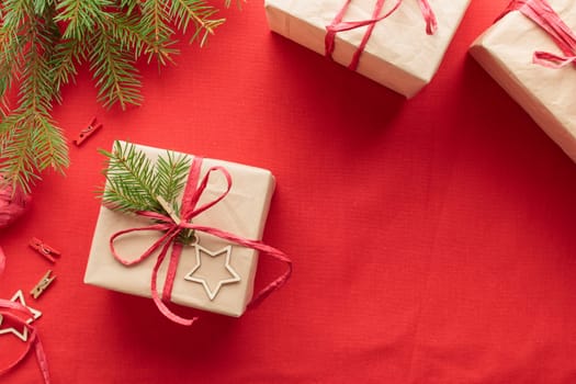 Christmas and zero waste, eco-friendly natural packaging gift boxes in craft paper on a red textile background, eco Christmas holiday concept, eco decor banner with copy space