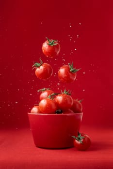 Creative food concept. Tomatoes pattern. Flying red ripe juicy cherry tomatoes with water drops on red background. Healthy fresh vegan organic food, vegetable, summer, harvesting