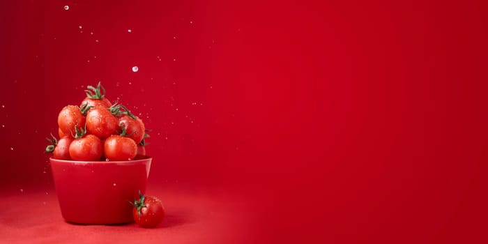 Creative food concept. Tomatoes pattern. Red ripe juicy cherry tomatoes in red bowl with water drops on red background. Healthy fresh vegan organic food, vegetable, summer, harvesting with copy space