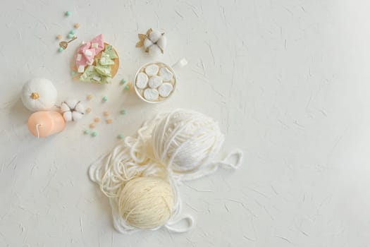 A delicate arrangement of yarn balls, pastel colored beads, and crafting materials on a light textured surface.