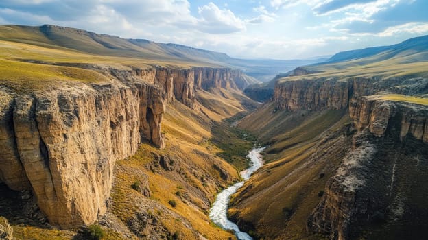 A winding river carves its path through a stunning canyon, surrounded by towering cliffs and expansive grasslands under a bright blue sky.