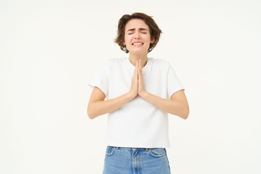 Desperate woman praying, begging for help, pleading, making wish, standing over white background.