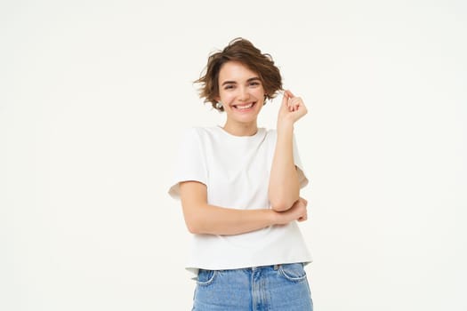 Portrait of carefree woman laughing, posing with confidence, looking self-assured and smiling, standing over white background. copy space