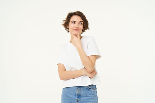 Portrait of thinking girl, smiling and pondering, making decision, contemplating something, standing over white background.