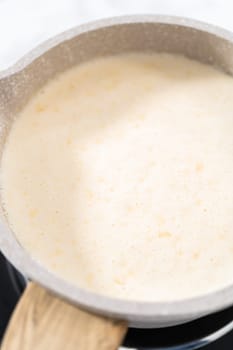 Heating whipped cream in a saucepan to make the white chocolate ganache frosting.