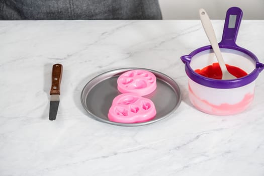 Filling silicone mold with melted chocolate to make chocolate lips and heart-shaped chocolates for Valentine's Day.