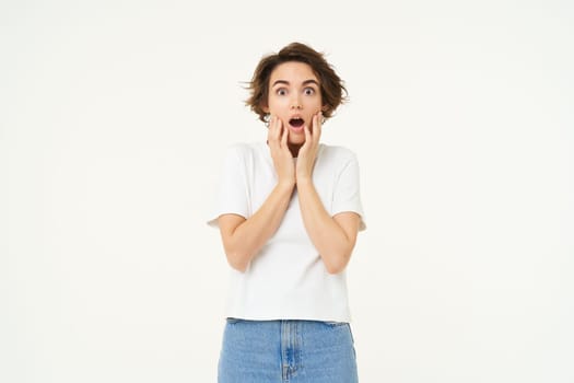 Image of woman with shocked face, looks frightened in panic, stands against white studio background. Copy space