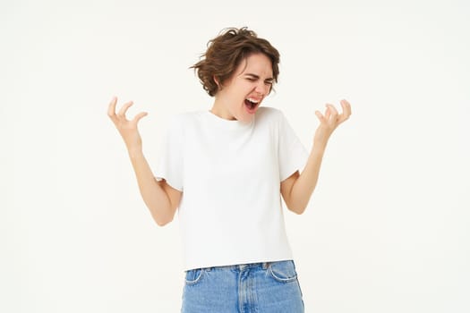 Portrait of woman throwing tantrum, shouting and screaming, shaking hands and yelling outraged, standing over white studio background.