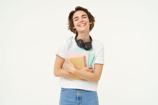 Image of carefree, smiling woman with notebooks, laughing and looking happy, posing over white background.