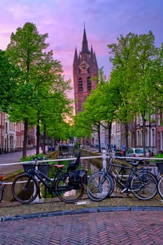 Delt street with bicycles on bridge over canal on sunset in dusk. Delft, Netherlands