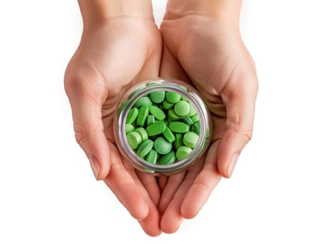 Two hands gently hold a clear jar of green pills, emphasizing a focus on health and wellness. The bright colors contrast beautifully against the plain background.