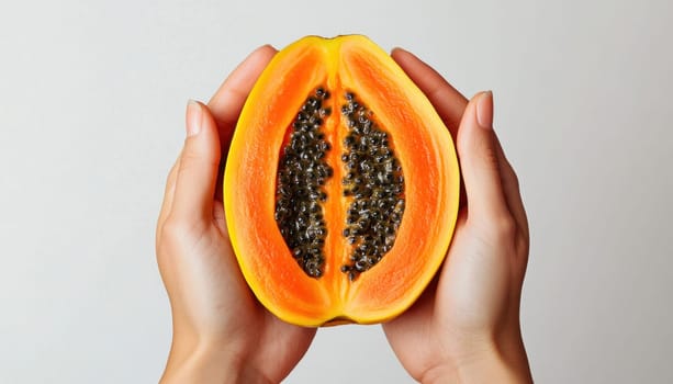 Woman is holding a half of ripe papaya fruit on a white background