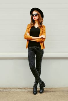 Fashion young woman model wearing a black hat sunglasses over grey background
