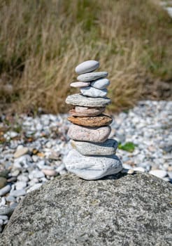 A tall stack of smooth stones on a pebbled surface, symbolizing balance and tranquility amidst a natural setting. Perfect for concepts of meditation, harmony, and simplicity