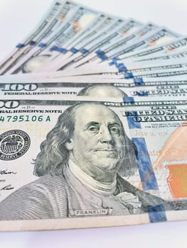 A Fan of $100 Bills.A close-up photo of a fan of $100 US dollar bills. The bills are arranged neatly, with the portrait of Benjamin Franklin visible on each bill. The background is white.Finance ve economy concept.