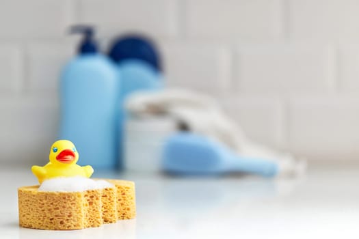 Yellow rubber duck, soap, bath foam on bath background, children bath accessories
