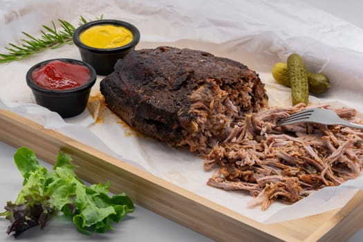 Tender, delectably pulled beef served generously with various flavorful sauces and pickles on a rustic wooden platter