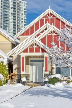 A perfect neighbourhood. Modern high-rise and private residential house in snow on winter season in British Columbia, Canada.