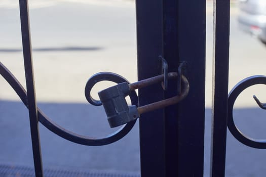 black metal forged gates closed with padlock. home security. reliability.