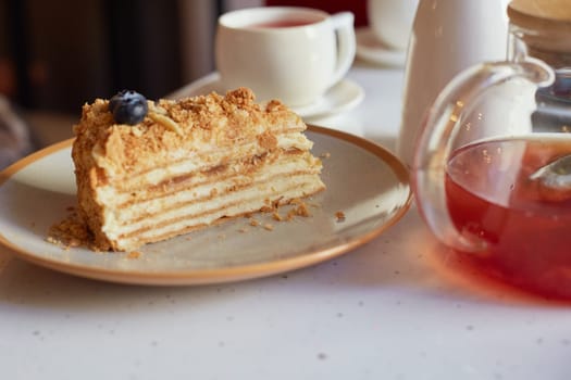 A piece of delicious fresh cheesecake on the table with a transparent teapot in the cafe. Delicious pastries, with a cup of hot tea. It's tea time. A sweet dish