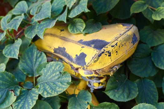 Photo of background with details of an old yellow retro bike. Saddle