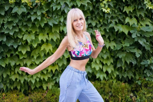 Female caucasian young professional dancer expressing movement through dance next to an urban garden