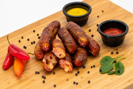 Delicious, savoury grilled sausages are beautifully served with mustard, ketchup, and fresh peppers on a wooden board