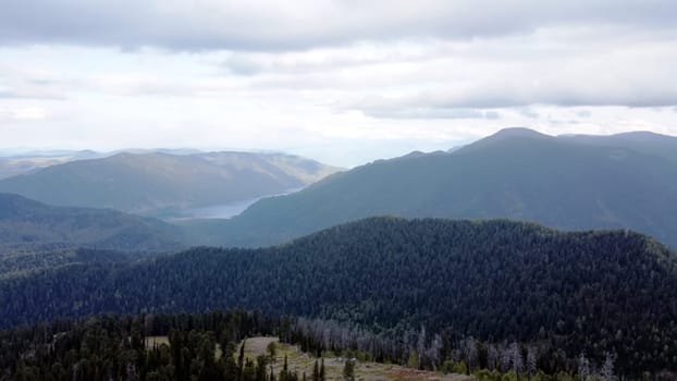 a mountain breathtaking river flows through the tranquil plain under the large clouds somewhere in the mountains, aerial panoramic view with no people
