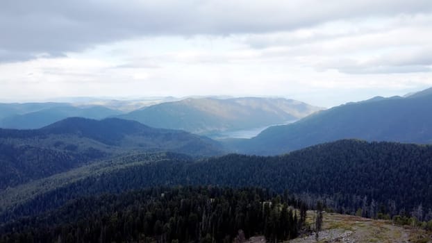 a mountain breathtaking river flows through the tranquil plain under the large clouds somewhere in the mountains, aerial panoramic view with no people