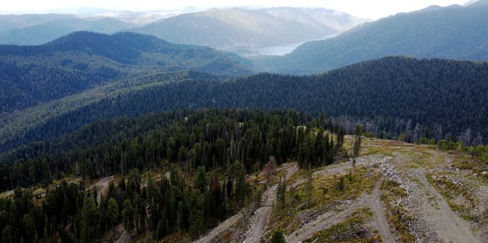 a mountain breathtaking river flows through the tranquil plain under the large clouds somewhere in the mountains, aerial panoramic view with no people