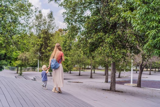 Mother with her toddler son walking in the park. Family bonding, outdoor exploration, and parenting concept.