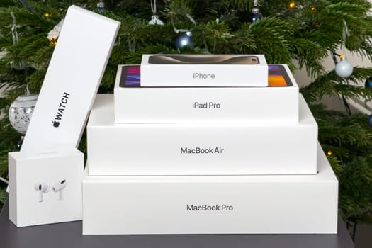 BERLIN , GERMANY - JANUARY 14 2024: Gift boxs with air pods, Apple watch, Macbook Pro, Macbook Air, iPad pro and iPhone under Christmas tree.