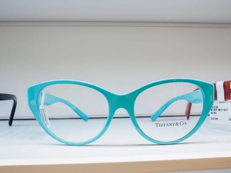Pair of tiffany and co. Teal cat eye eyeglasses are sitting on a shelf in an optometrist shop, awaiting their owner