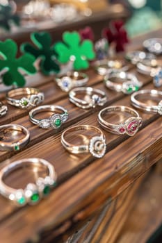 Traditional claddagh rings displayed on a wooden table at a st. patrick's day market, surrounded by vibrant green clover decorations. a mix of elegant designs featuring intricate details and colorful gemstones.