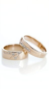 Two simple gold wedding rings are laying on white cloth, ready for the couple to exchange during their wedding ceremony