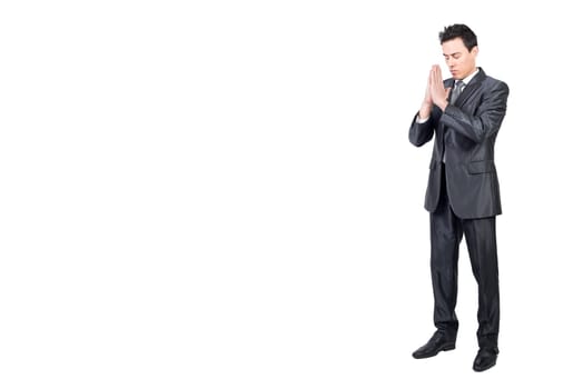 Full body of hoping peaceful male worker in classy suit standing with prayer hands in studio against white background