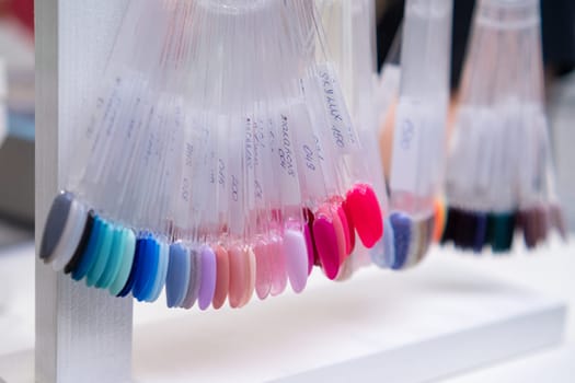Collection of nail gel polish on the transparent tips in a beauty salon.
